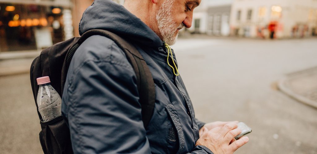 A man checks his cellphone on an empty street.