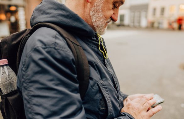 A man checks his cellphone on an empty street.