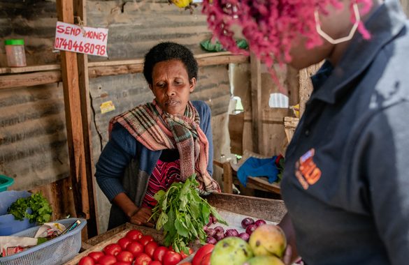 A Congolese produce vendor looks as Mercy Corps staff select fruit.