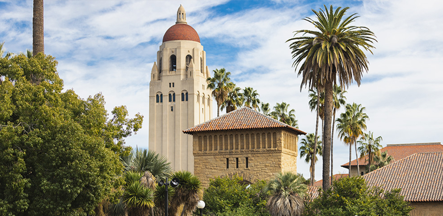 Stanford's Hoover Tower surrounded by palm trees on a partly sunny day